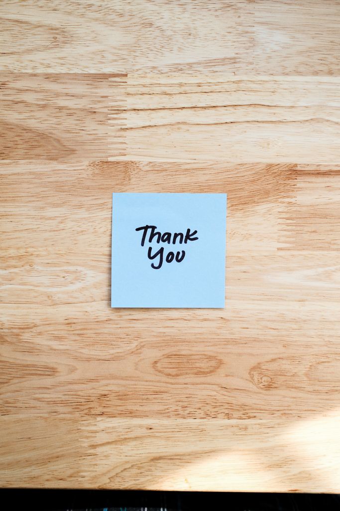 A handwritten 'Thank You' note on a wooden table, conveying gratitude.
